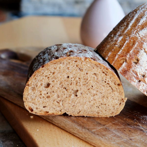 Lund-Sylt-Bio-Roggenmisch-70-30-Roggensauerteig-anschnitt.png Eine Nahaufnahme von BIO MISCHBROT 500 g auf einem Holzbrett zeigt seinen rustikalen Bio-Look mit weicher Kruste und knuspriger Außenseite.