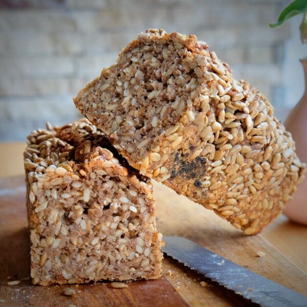 Sonnenblumenkern-Stange-Friesen-Voillkornbrot-Lund-Sylt-Sauerteig-1-3.jpg Ein aufgeschnittener Laib BIO SONNEN-BLUMEN-STANGE liegt auf einem Schneidebrett, daneben liegt ein Messer.